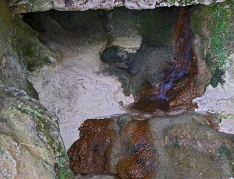 La résurgence principale  On note des dépots de fer (rouges) et de calcite (blancs)