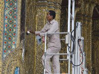 Un ouvrier époussetant les mosaiques de Wat Phra Kaew avec un pinceau (Bangkok)